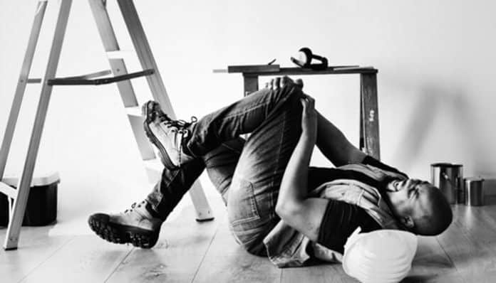 A worker lying on the floor after an accident near a ladder, highlighting the importance of safety training to prevent workplace accidents