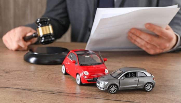 Houston auto accident attorney reviewing car crash case evidence with miniature car models and legal documents on desk.
