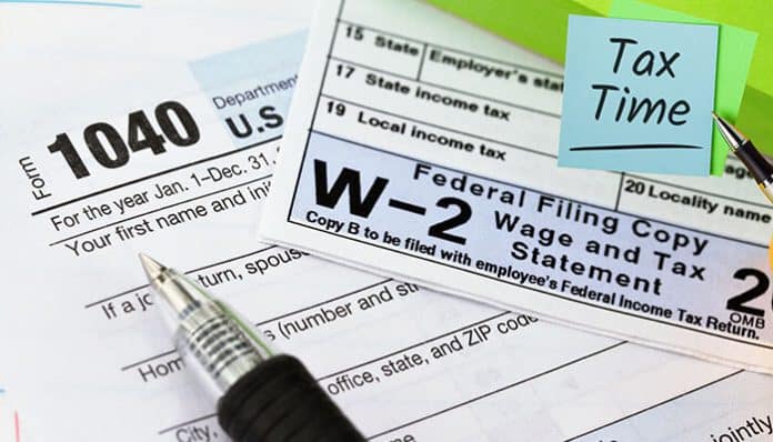 A close-up view of tax documents including Form 1040 and a W-2 form with a pen and a sticky note reading Tax Time, representing the ease of filing taxes using a W-2 generator