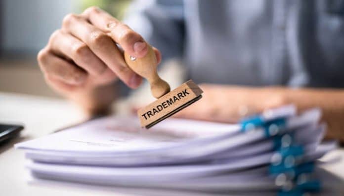 Person stamping legal documents with the word Trademark, symbolizing how to register a trademark in India for brand protection and legal right