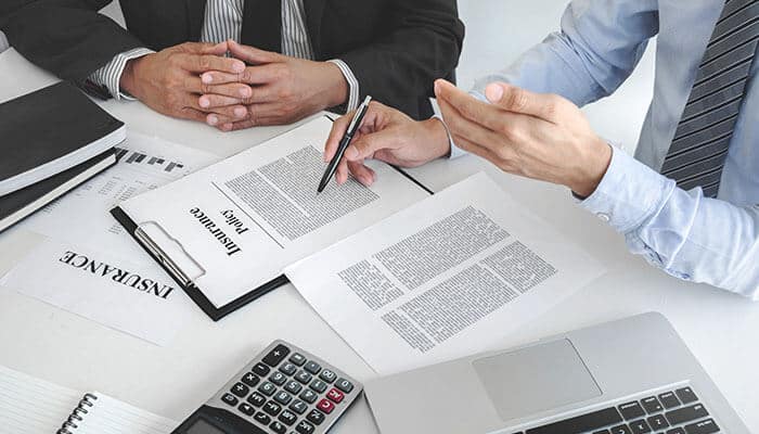 Lawyer reviewing insurance policy documents with client during personal injury settlement discussion.