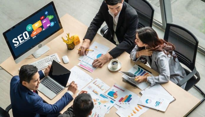 Team discussing strategy around charts and reports, showing how managing organizational change while adopting enterprise SEO services drives business growth.