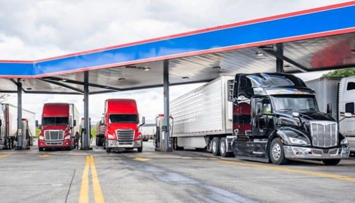 Trucking industry accident prevention is crucial as trucks refuel at a service station, underscoring the importance of vehicle maintenance and safety in the trucking sector
