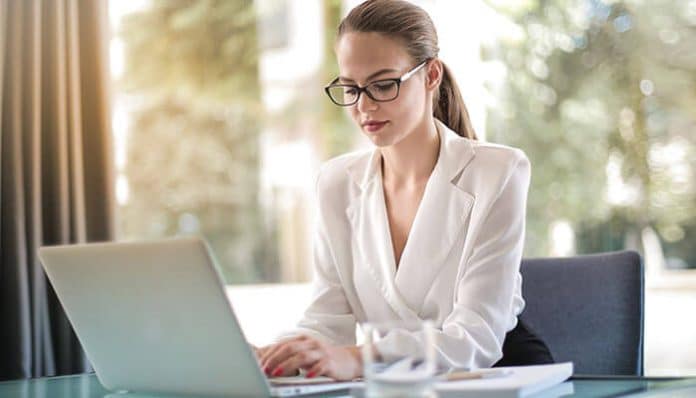 A professional entrepreneur working on a laptop in a modern office, representing productivity and growth while applying essential startup tips for budding entrepreneurs.