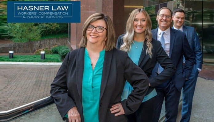 Hasner Law team of attorneys standing together outside the office building, smiling and dressed professionally in suits, with the Hasner Law logo displayed in the top left corner