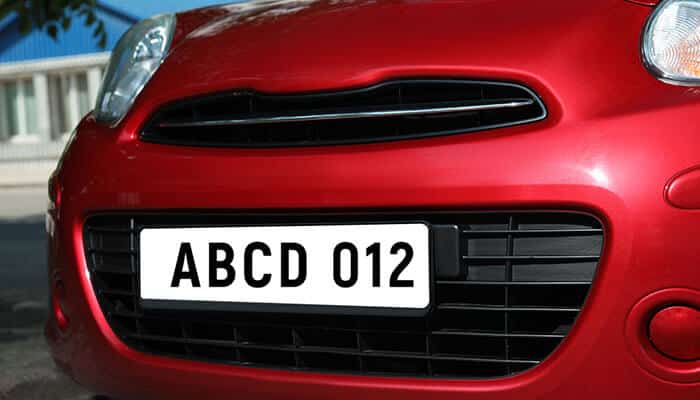 A close-up view of a red car with a customized registration plate, illustrating the idea of adding a private plate on my finance car