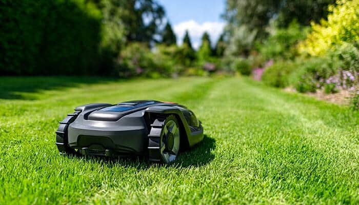 Robotic electric lawn mower trimming grass in a garden for effortless lawn care.