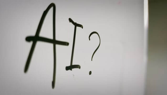 The handwritten text “AI?” on a whiteboard symbolizing curiosity and exploration around Generative AI For 24/7 Support in modern startups.