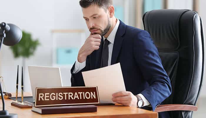 A business professional reviewing documents at a registration desk, representing online company registration procedures.