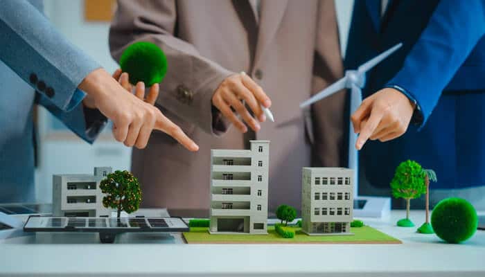Professionals are trying to collaborate with local startups, pointing at miniature models of sustainable buildings and green spaces to discuss urban development and innovation