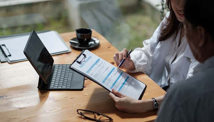 A student reviewing and filling out an insurance form with guidance, emphasizing the need for health insurance abroad for students when studying overseas.