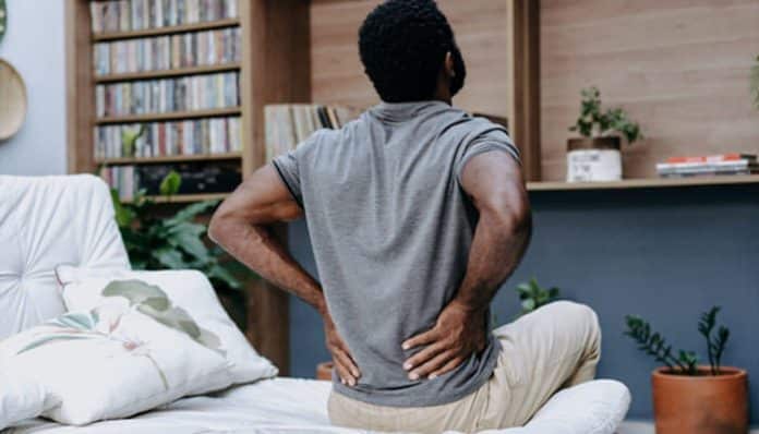 Injured person holding lower back in pain at home, illustrating evidence for pain and suffering claims in a personal injury case