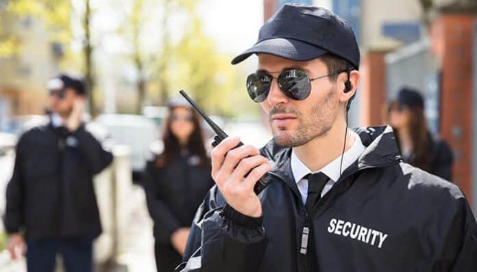 Security officer patrolling in security with a walkie-talkie and sunglasses, ensuring safety and monitoring the area