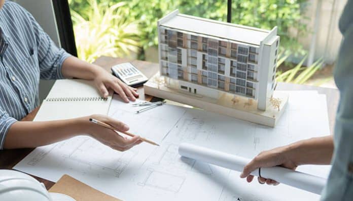 Architects discussing blueprints with a building model on the table, illustrating the concept of functional architecture that blends design creativity with structural purpose