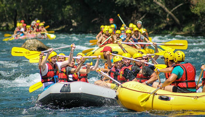 Group of people white water rafting on a fast river in New Zealand for adventure seekers looking for thrilling outdoor activities