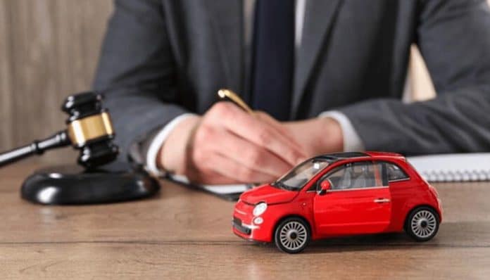 Car Accident Claim process illustrated by a legal professional reviewing documents beside a model car and gavel, representing insurance and legal evaluation