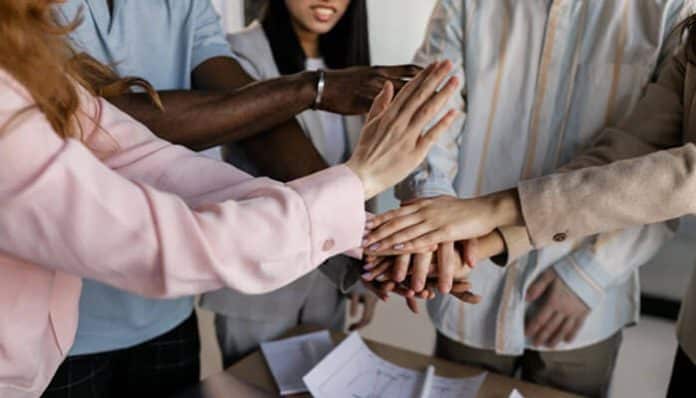 A group of diverse team members collaborating and supporting each other, demonstrating ways to motivate startup teams through teamwork and shared effort.