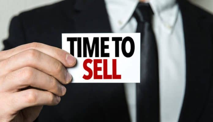 How to sell a business note illustrated by a seller holding a time to sell sign