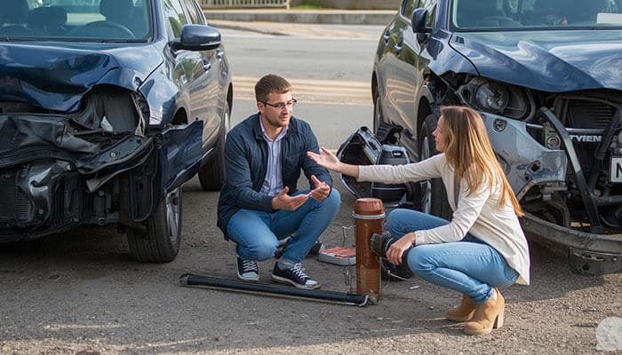 Admitting Fault - Startupeditor | Startup Editor Car Accident Claim discussion at a crash scene, showing two drivers talking beside damaged vehicles after a collision