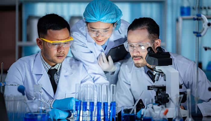 Scientists in a laboratory analyzing samples with microscopes and test tubes, demonstrating how advanced tools like Agilent FTIR spectroscopy instruments support precise research workflows