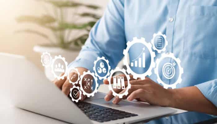 Person typing on a laptop with performance icons illustrating automating performance reviews