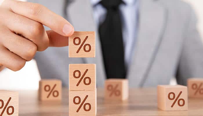 Person stacking wooden blocks with percentage symbols, representing interest rates and the financial aspects of payday loan in Singapore