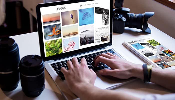 Laptop displaying a professional photography portfolio with camera gear on the desk, illustrating how to start a photography business online