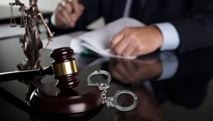 Criminal Lawyer in Bloomington, IL reviewing legal documents with gavel and handcuffs on desk