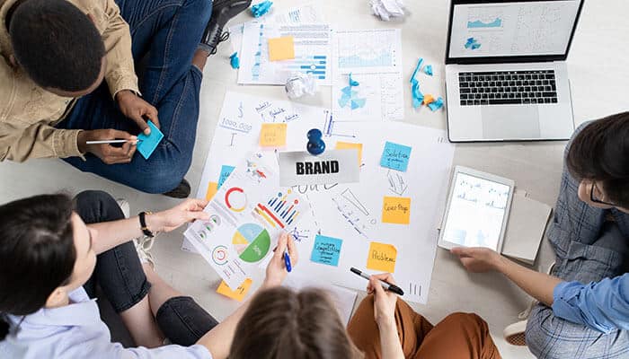 Team of people collaborating with charts, graphs, and post-it notes, working together to build a brand from scratch and strategize brand development