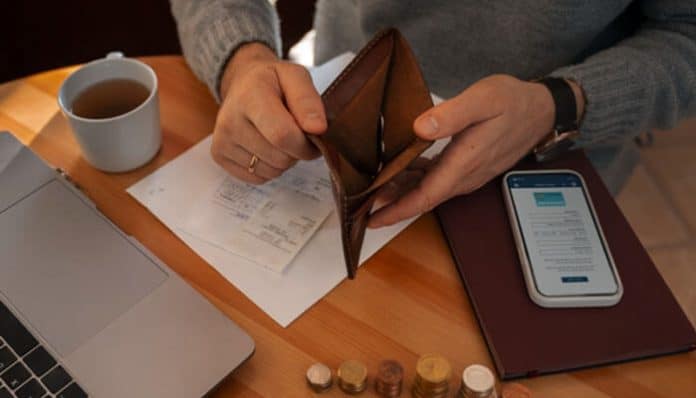 Person reviewing their finances with an empty wallet, highlighting out-of-pocket costs and financial stress after an accident
