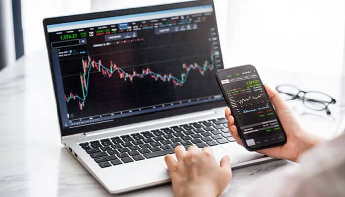 Forex Trading analysis showing a trader monitoring live currency charts on a laptop and smartphone for real-time market decisions