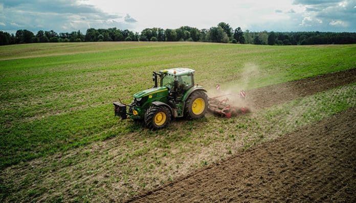 Tractor using a modern mulcher to work on a large field, showcasing the power and efficiency of modern mulchers for tractors in agricultural land management