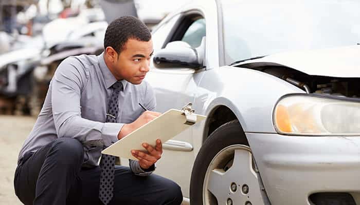 Insurance adjuster inspecting a damaged vehicle after a highway accident, related to maximizing compensation in highway accident claims.