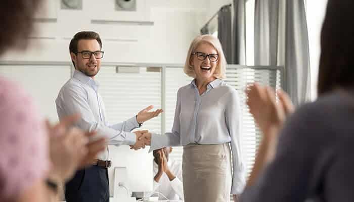 Two professionals shaking hands in celebration, symbolizing motivation and recognition within a startup team, key elements to motivate startup teams.