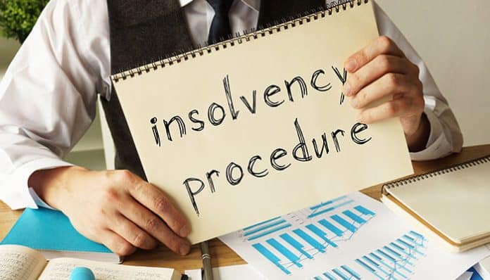 A person holding a sign that says insolvency procedure illustrating business recovery and insolvency