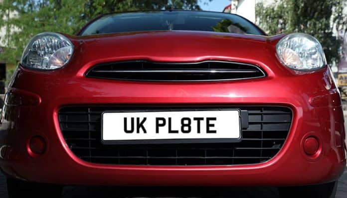 Close-up of a red car with a private number plate, displaying 'UK PL8TE'. Private number plates offer a unique way to personalize your vehicle.