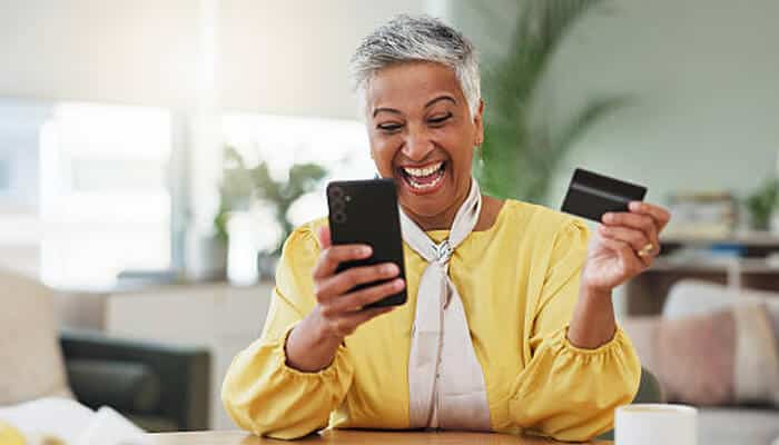Excited woman holding a smartphone and a smart card, showing the success of smart card upgrades in digital banking