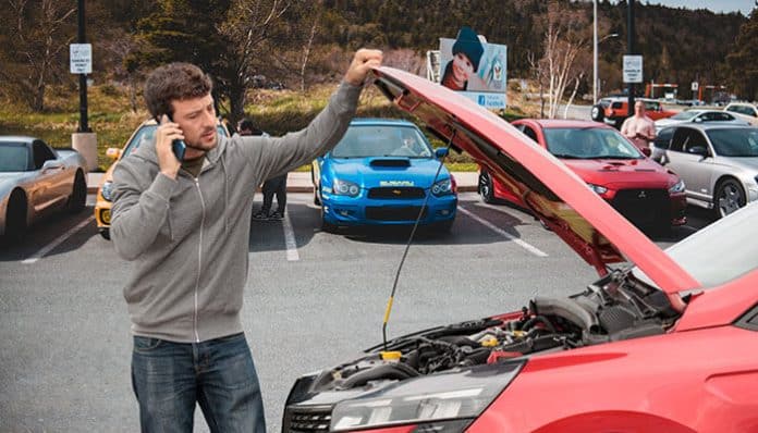 Person on the phone assessing their car's engine, representing the challenge of afford car repairs and the need for effective strategies to manage unexpected costs