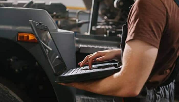 Mechanic using a laptop to diagnose vehicle issues, an essential tool for modern car mechanic business operations