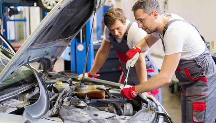 Car mechanics working on a vehicle engine in a workshop, essential for a successful Car Mechanic Business