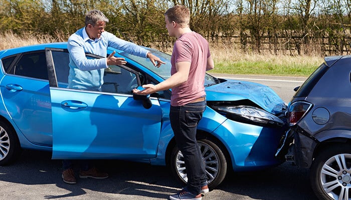 Two drivers arguing after a car crash, illustrating why certain phrases to avoid after a car crash can affect your legal case and insurance claims.