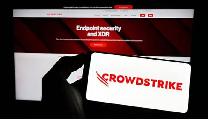 A smartphone displaying the CrowdStrike logo in front of a computer screen showing endpoint security and XDR information, representing research into leading CrowdStrike competitors in the cybersecurity market.