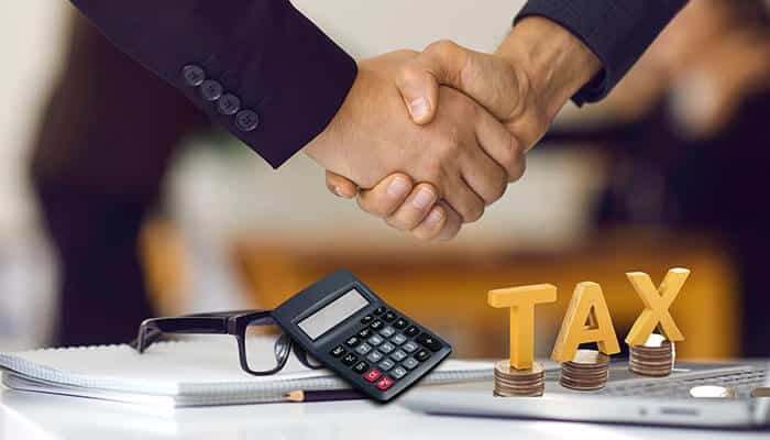 A handshake between two professionals, symbolizing trust and partnership with Marion CPAs, along with tax-related items such as a calculator and coins