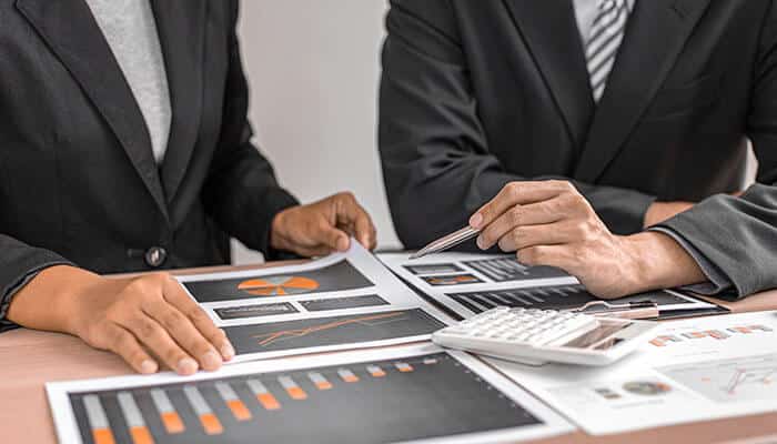 Business professionals analyzing financial charts and reports, emphasizing the importance of reducing friction in withdrawal for efficient payment processing and decision-making