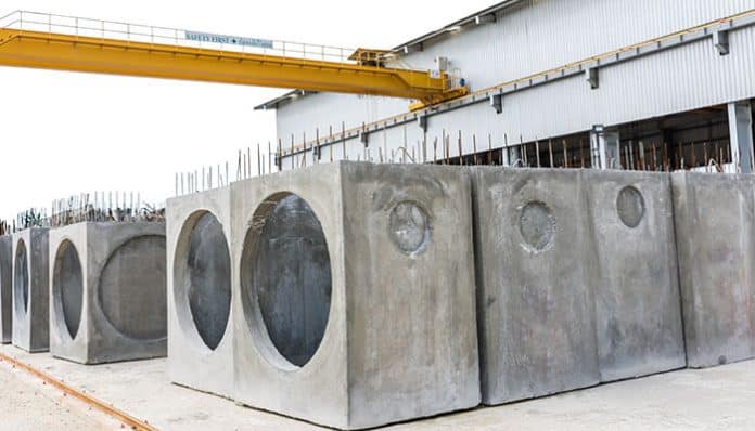 Large precast concrete pits with circular openings displayed at a construction manufacturing site