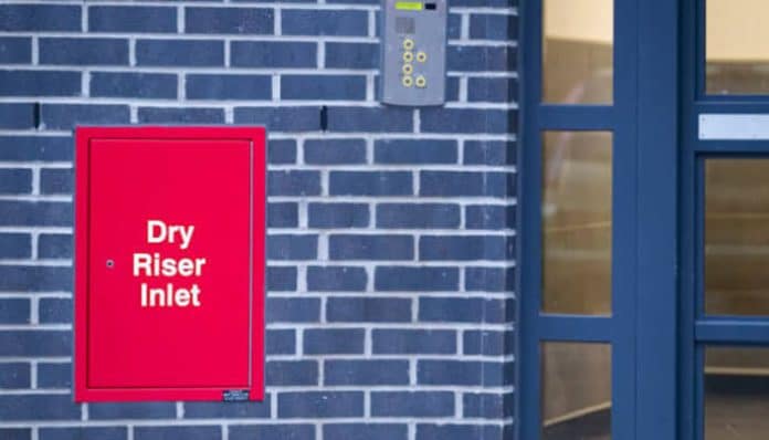 Riser cupboard labeled 'Dry Riser Inlet' on a building wall, demonstrating compliance with fire safety regulations and showcasing a riser cupboard that pass inspection