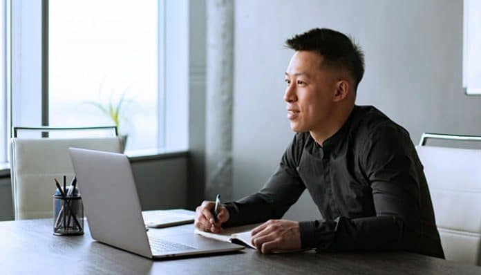A Node.js developer working at a desk with a laptop, illustrating the process of hiring skilled developers for cloud-native serverless applications