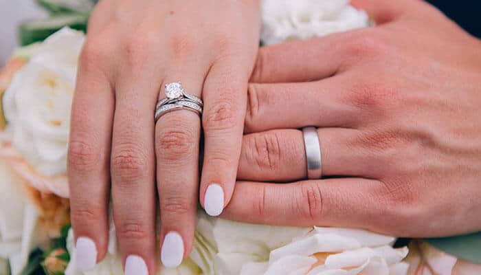 Engagement Ring Purchases displaying a couple’s hands with wedding bands and an engagement ring, emphasizing the emotional and financial commitment involved