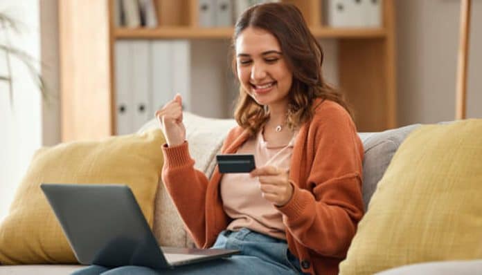 Happy woman using a laptop and holding a smart card, celebrating successful smart card upgrades in digital banking.