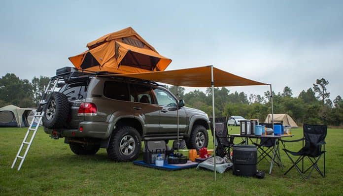 Buying a Rooftop Tent for road trips with an SUV rooftop tent setup, ladder access, awning shade, and outdoor camping gear arranged beside the vehicle
